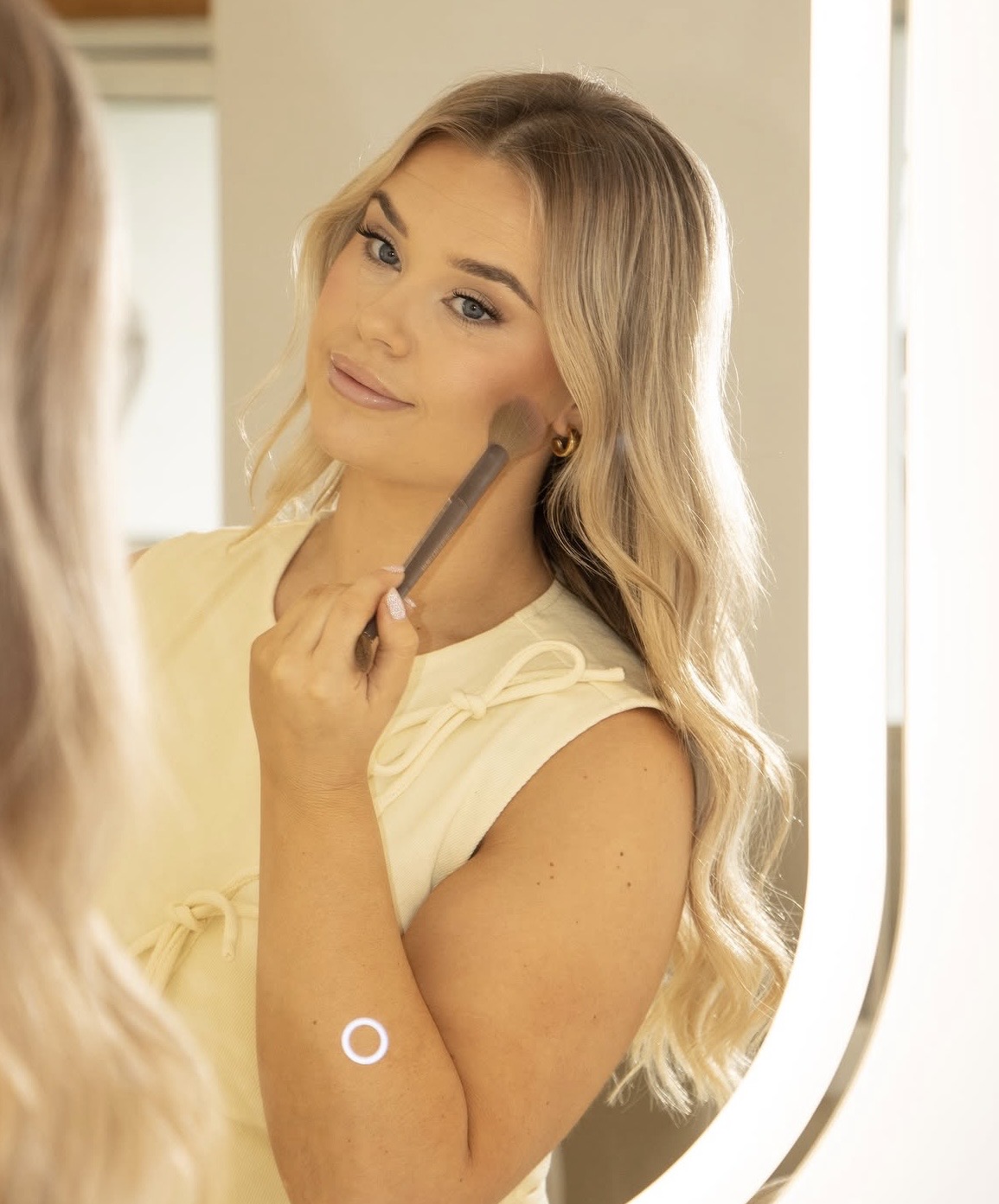 Hannah applying makeup in the studio mirror
