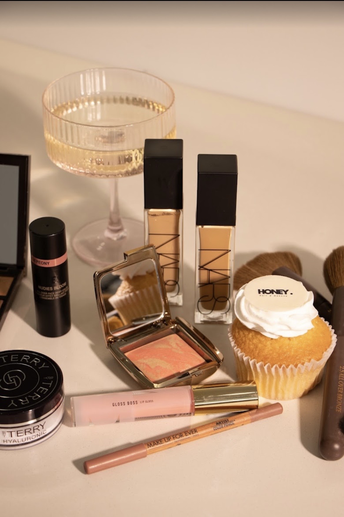 Makeup products and a HONEY. cupcake on the styling bench